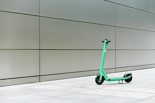 A green complete scooter parked at the corner of the street