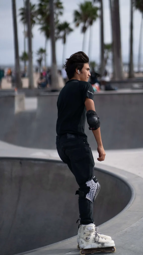 A man in black pants and shirt wearing elbow and knee pads
