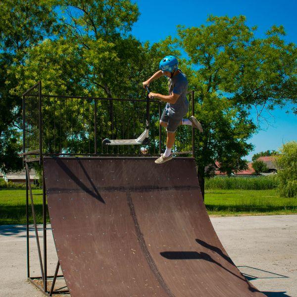 A man with blue helmet performing the air trick on a ramp in the skate park