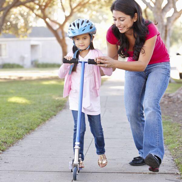 Mother being patient with her daughter while teaching how to scooter 