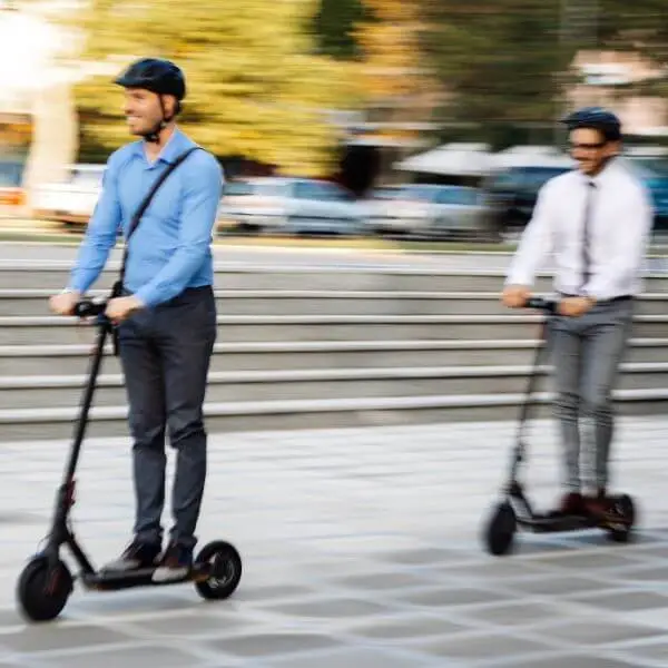2 men in pant shirt riding scooters, as scooters are better than skateboards in mobility