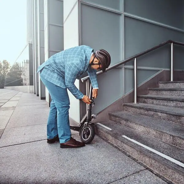 A man locking his EScooter to a fixture showing how to keep your scooter from being stolen